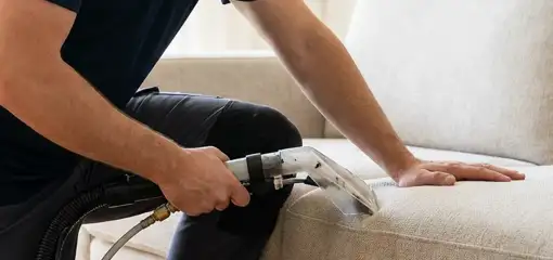 Professional upholstery cleaner deep-cleaning a fabric sofa with a handheld extraction tool, Lowell, MA.